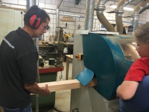 man working wood machine watched by boy