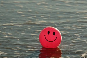 Red ball with smiley painted face in sea