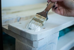 Person painting wood ice blue with brush 