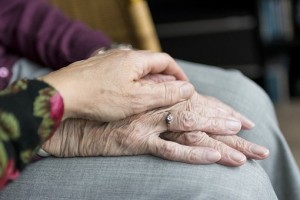 Care giver holding older person\s hand