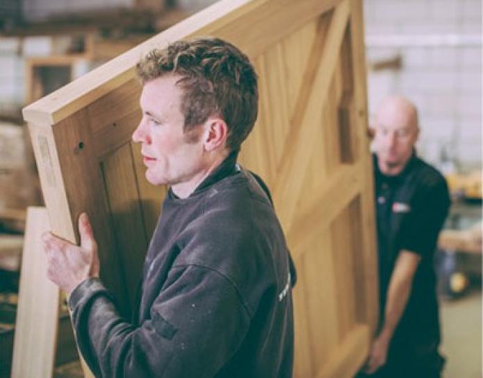 John Bright craftsmen carrying large wooden gate