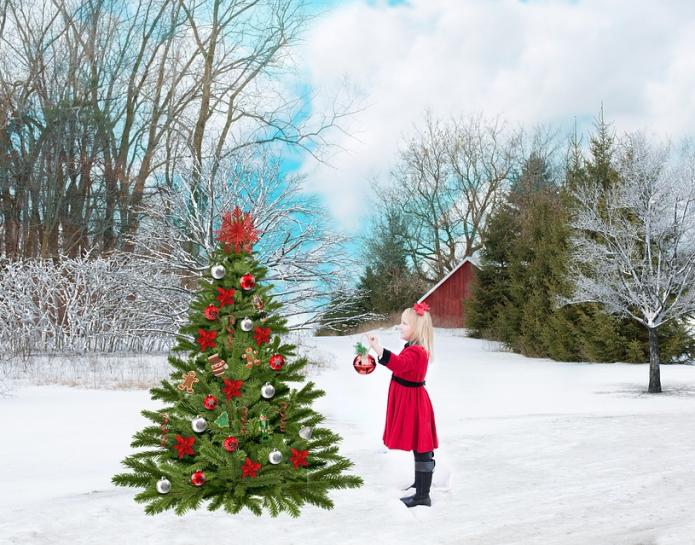 Decorated Christmas tree in snow with girl in red